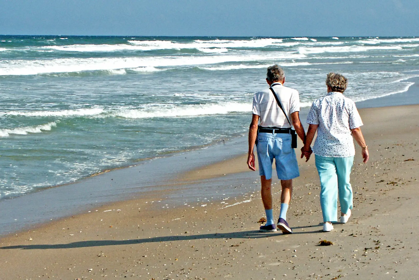 Älteres Paar geht Hand in Hand am Strand entlang