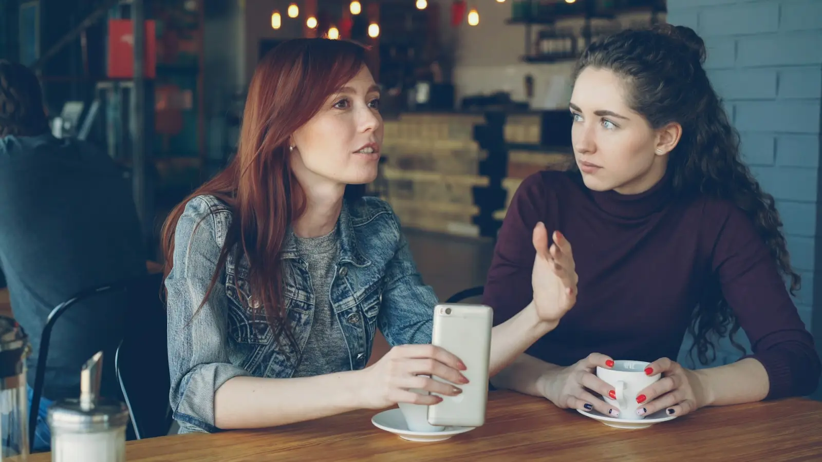 Zwei Frauen im Gespräch an einem Cafétisch