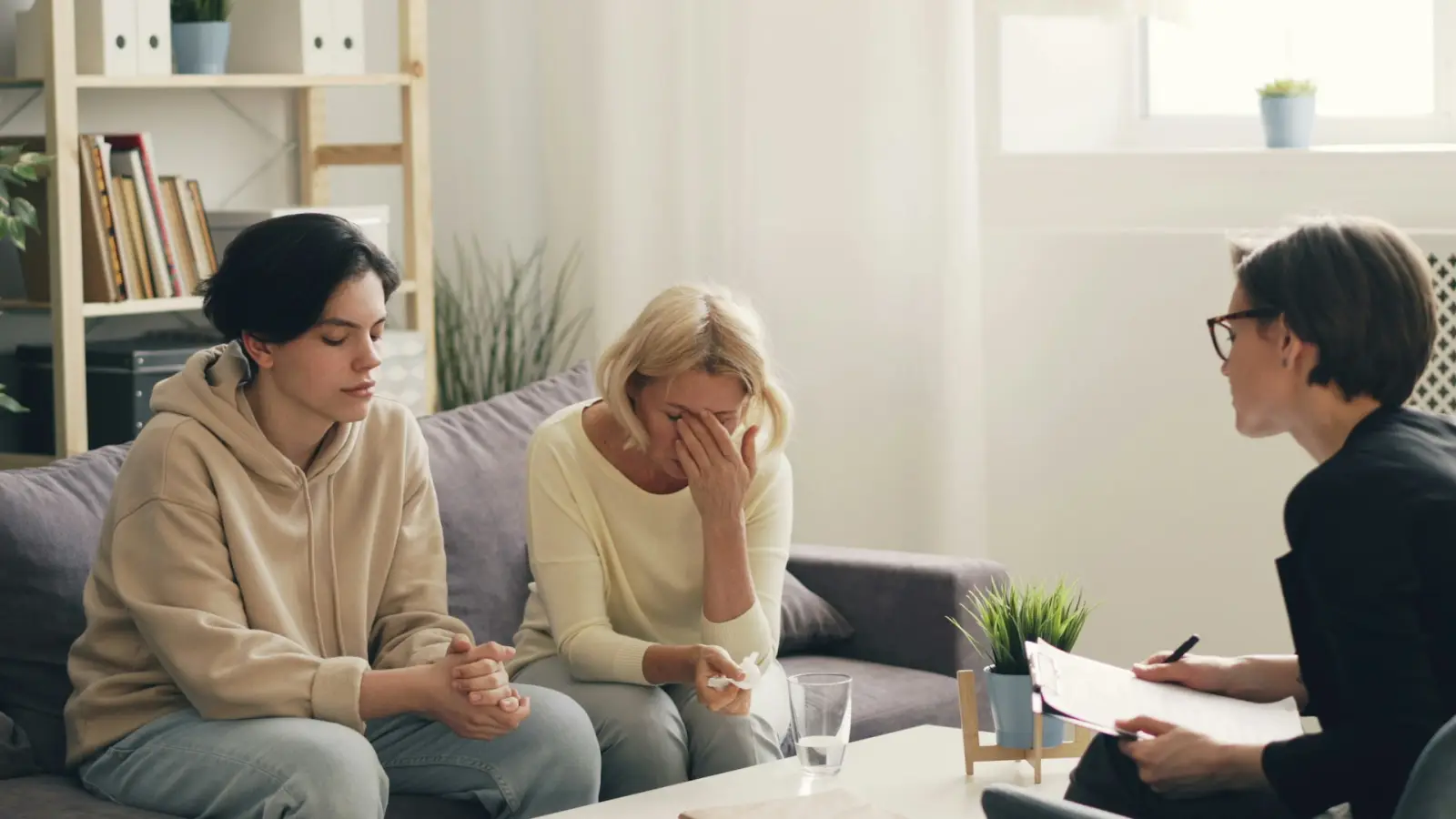 Zwei Frauen im Gespräch auf einem Sofa, auf dem Tisch Unterlagen
