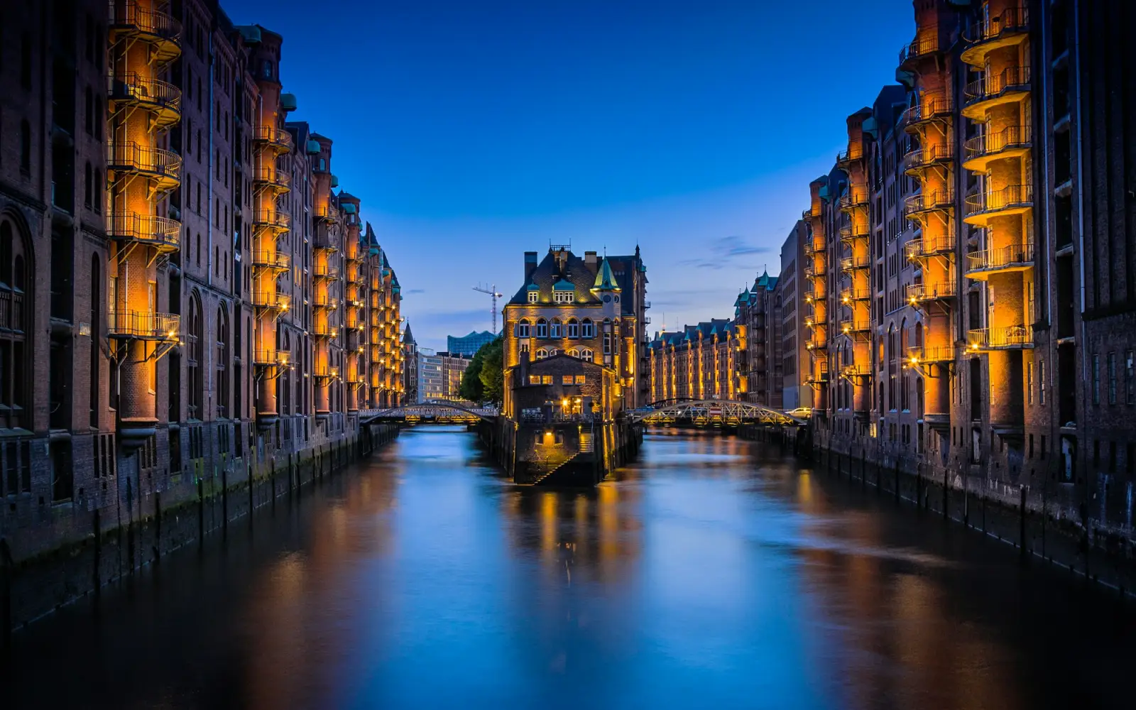 Speicherstadt in Hamburg zur blauen Stunde: beleuchtete Backsteinspeicher und das Wasserschloss am Fleet