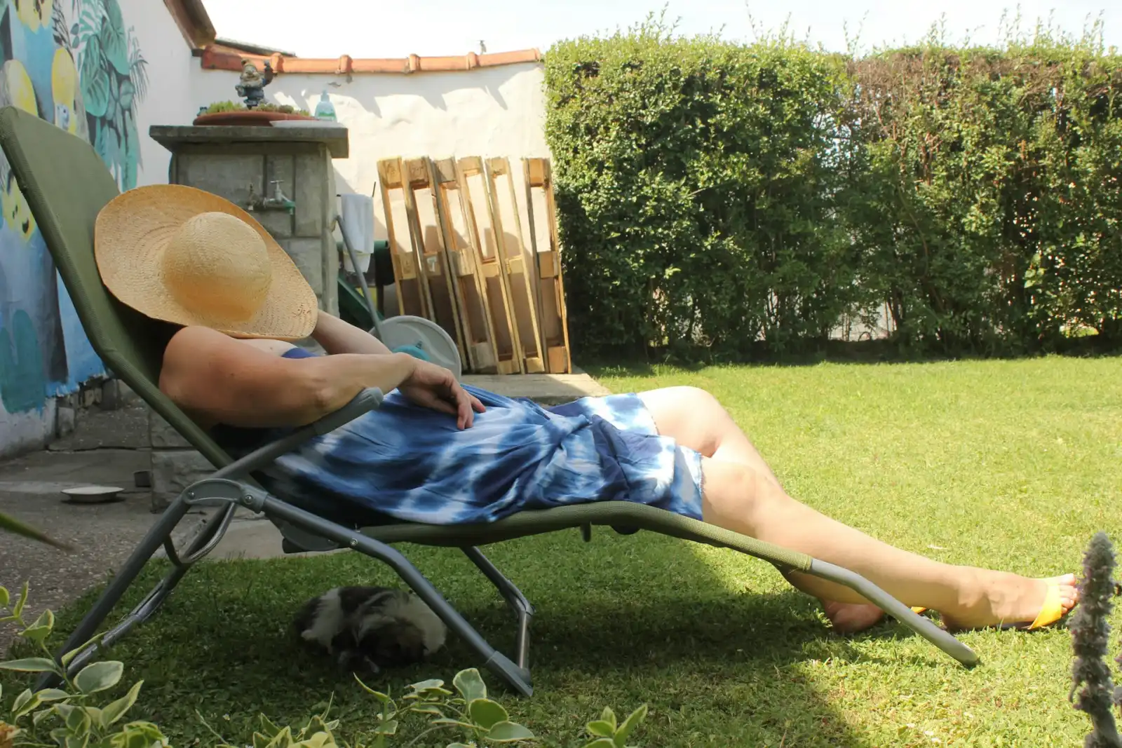 Person liegt auf einem grünen Liegestuhl im Garten in der Sonne